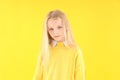 Resentful little girl in sweater on yellow background