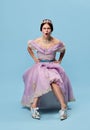 Resentment. Expressive young girl in lilac color medieval dress as young queen or princess looking at camera, giving