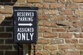 Reserved Parking and Assigned Only sign against a red brick wall