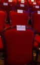 Reserved red velvet chairs in an auditorium.