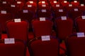 Reserved red velvet chairs in an auditorium.