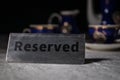 Reserved sign on the table. A tag of reservation placed on the wood table. Metal tag with reservation on dark. Reserved table in a Royalty Free Stock Photo
