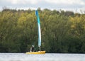 Reservoir small yellow sail boat on clean blue lake water in sunshine. Sailing alone. Royalty Free Stock Photo