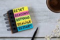 Reset, readjust, refocus, realign, restart, inspirational text in notebook with coffee cup on wooden background Royalty Free Stock Photo