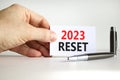 2023 Reset symbol. White paper with words 2023 Reset. Businessman hand. Metallic pen. Beautiful white table white background.