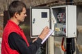 A resident of a country house takes readings of an electric energy meter Royalty Free Stock Photo