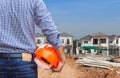 Resident engineer holding yellow safety helmet at new home building under construction site Royalty Free Stock Photo