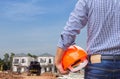 Resident engineer holding yellow safety helmet at new home building under construction site Royalty Free Stock Photo