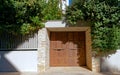 A residential apartment building entrance brown metal door by the sidewalk and green foliage. Royalty Free Stock Photo