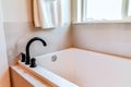 Residential bathroom interior with built in rectangular bathtub beside window Royalty Free Stock Photo