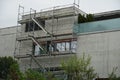 Residential building, modern and small with scaffolding on one of the walls to repair the terraced roof