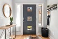 Residential entryway of a house with a gray door, hanging umbrellas, and a round mirror