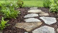 Residential garden walking path with flat stones, mulch and green plants Royalty Free Stock Photo