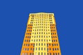 Residential high-rise building with many glass windows standing against background of blue sky and sun. Urban real Royalty Free Stock Photo