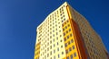 Residential high-rise building with many glass windows standing against background of blue sky and sun. Urban real Royalty Free Stock Photo