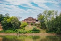 Residential house on a hill surrounded by trees by a pond Royalty Free Stock Photo