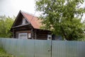 Residential old wooden house behind an iron high fence