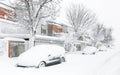 Residential street completely snowed in with snow-covered cars parked at the entrance to the houses. Winter landscape