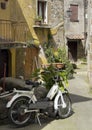 Residential street with a parked electric bicycle and potted plants in a neighborhood of Pitigliano, Italy.