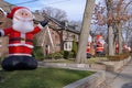 Residential street with a proliferation of giant inflatable Santa Claus dolls