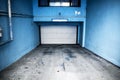 Residential underground garage with white door and blue walls. Parking under the residential building Royalty Free Stock Photo