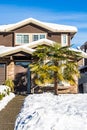 Residentional house entrance in snow with tropic palm tree in front.