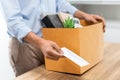 Resignation Concept The male officer standing, putting his box of his belongs on the desk and handing the white letter to someone