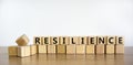 Resilience symbol. Word `Resilience` written on wooden blocks. Copy space. Beautiful wooden table, white background. Business an