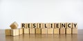 Resiliency symbol. Word `Resiliency` written on wooden blocks. Copy space. Beautiful wooden table, white background. Business an