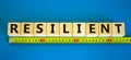 Resilient symbol. Resilient word on wooden cubes arranged behind the yellow ruler on beautiful blue background. Business, Royalty Free Stock Photo
