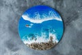 Resin art round painting. Epoxy art composition with blue ocean waves, boat and stones beach. Flat lay, top view