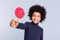 Resolute dark-haired joyful boy pulling out hand with candy in it