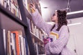 Resolute good-looking girl in round glasses getting book