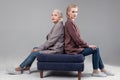 Resolute serious women sitting on blue sofa back to back