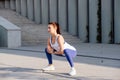 Resolved woman working out on the street, doing squats