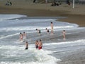 Young People Play in Ocean as the Surf Rolls in and Back Out
