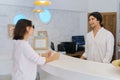 Resort hotel front desk, woman guest talking to man working at reception Royalty Free Stock Photo