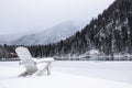 A resort on the lake in winter. Wooden chairs in the snow by a frozen lake.