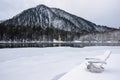 A resort on the lake in winter. Wooden chairs in the snow by a frozen lake.