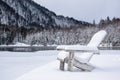 A resort on the lake in winter. Wooden chairs in the snow by a frozen lake.