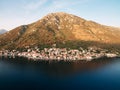 Resort town of Perast at the foot of the mountains in the rays of the setting sun. Montenegro. Drone