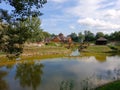 Resort view with houses, meadow, and trees around, a lake reflecting cloudy sky background