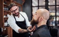 Respect the beard. a handsome young barber trimming and lining up a clients beard inside his barbershop. Royalty Free Stock Photo