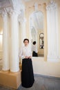 A respectable woman in ancient Ukrainian clothes, stands in the premises of a chic baroque estate