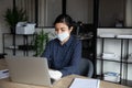 Responsible businesswoman working on computer in protective gloves and mask.