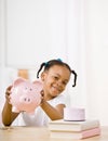 Responsible girl putting money into piggy bank