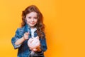 Responsible girl putting money into piggy bank for future saving Royalty Free Stock Photo