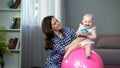 Responsible mother doing early development exercises with active baby girl