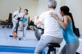 Responsible trainer helping her patient with an exercise bike