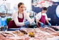 Positive saleswoman demonstrating calamary in fish store